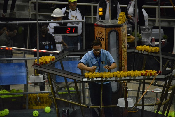 FIRST® Robotics participant places gears during competition