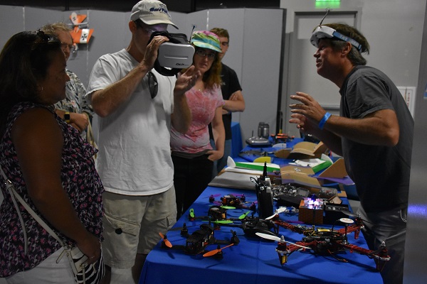 Man looks through VR goggles at drones while others watch 