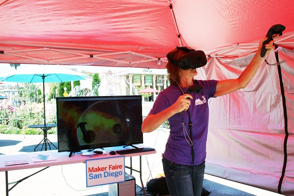 Woman in a purple T-shirt operates VR devices at Maker Faire® San Diego