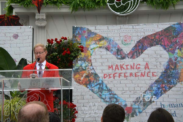 Tournament of Roses Presdient Lance Tibbet reads from lectern with "Making a Difference" banner behind him