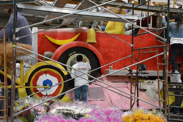 Staffer glues materials on a bright red car with "2018" on it