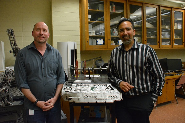 Alan Timm and Walter Martinez stand on either side of one of RSSC's early battling robots
