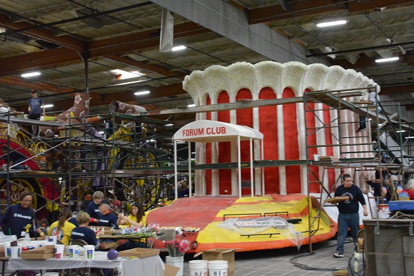 Red Forum Club float with white archway and volunteers working