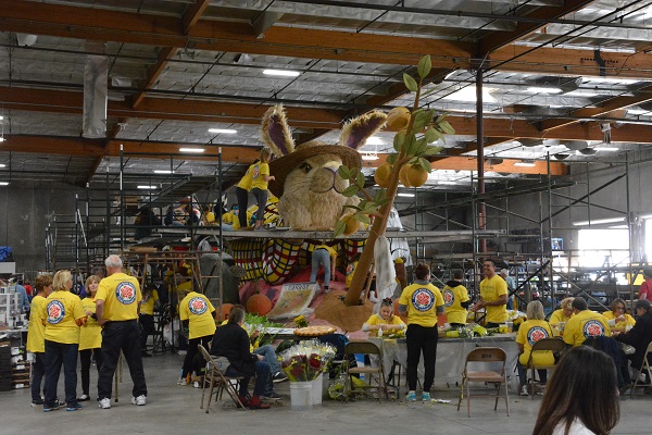 Volunteers in yellow Petal Pushers T shirts with red roses surround a rabbit float