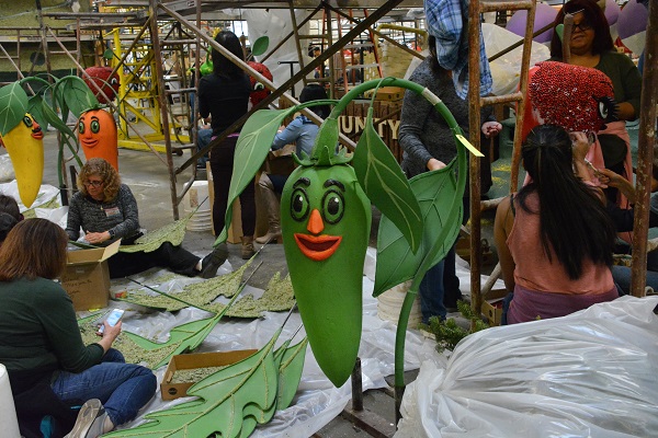 Volunteers paint glue on whimsical veggies at Fiesta Parade Floats