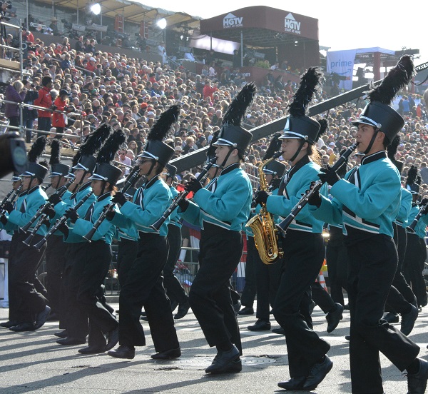 BOSS musicians in black slacks and aqua jackets play brass instruments before the reviewing stand