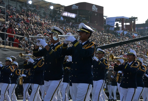 Banda De Musica musicians in navy blazers with white pants and caps playing brass instruments at the reviewing stand