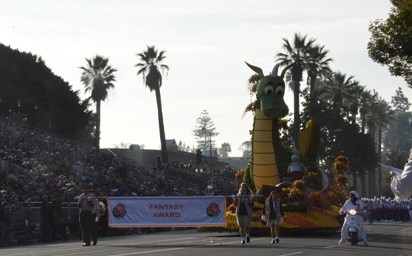 Chivalry float with green dragon rolse past audience and palm trees