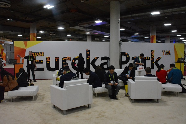 Eureka Park attendees in chairs in front of Eureka Park sign with Post-Its on it