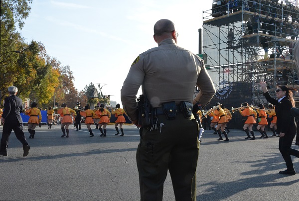 Green and members play brass instruments as their band runs around the corner of Colorado and Orange Grove