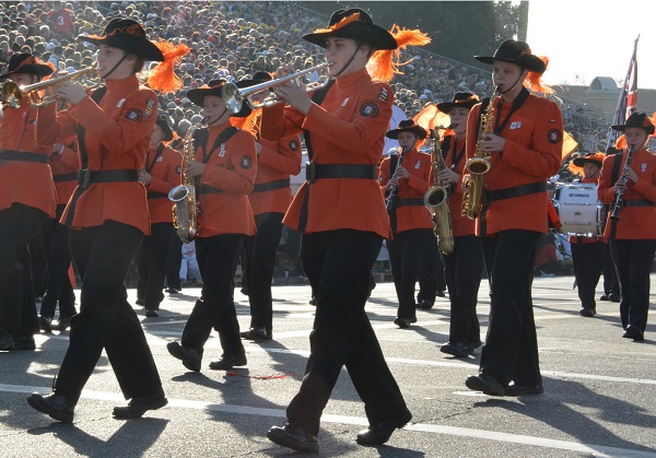 Marching Koalas play brass instruments as they march by the reviewing stand