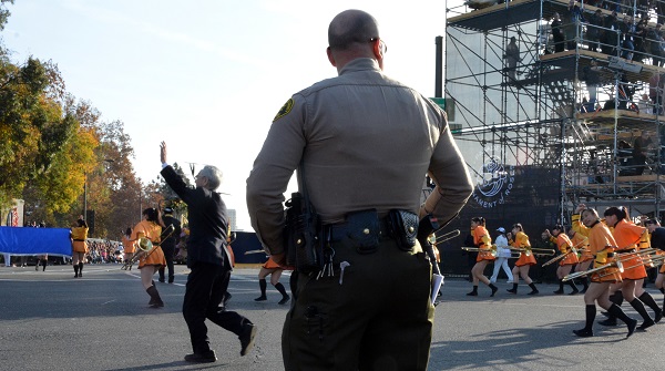 Band director waves as he and Green Band take the corner at Colorado and Orange Grove