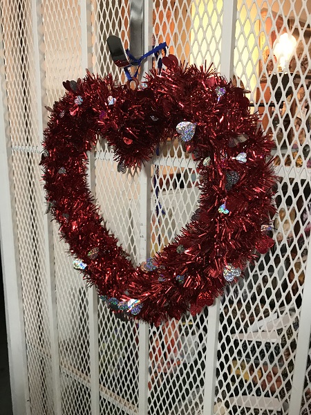 red and silver tinsel heart on white metal door at Pipe & Thimble Bookstore