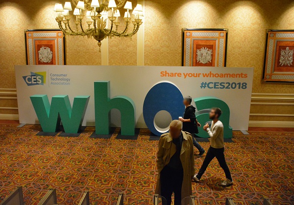 Attendees walk past "whoa" sign in convention hall during CES® 2018