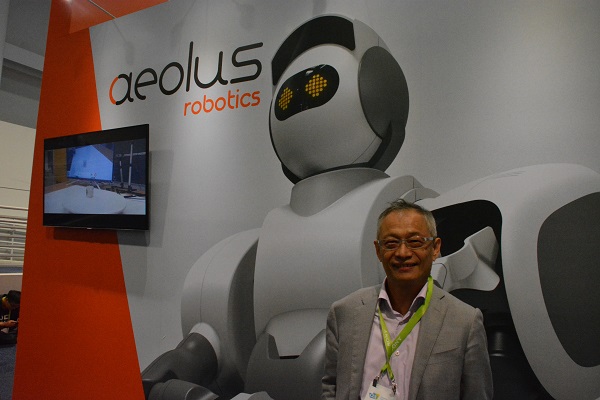 Aeolus Robotics founder and President alex Huang in front of an Aeolus robot display at CES 2018