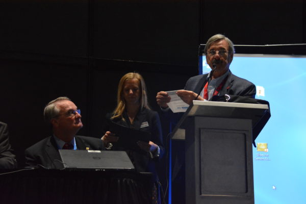 Medium shot of Roger Grace at lectern with Charlene Soucy and John Walz at Sensors 2018.