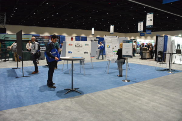 Students stand at tables in the University Zone whre their posters are displaye during Sensors 2018.