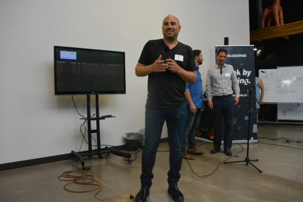 "Ideas Immersion" founder David Dorfman stands with two "BrightPaths" entrepreneurs at front of the room at the start of 2018 "Demo Day".