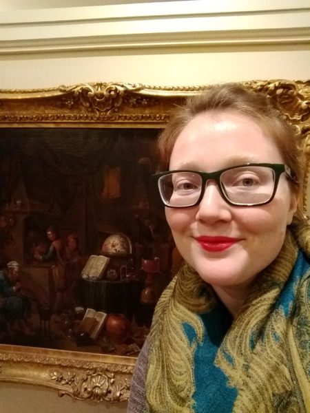 Dr. Elisabeth Berry Drago, curator of "Age of Alchemy", in front of a painting of a seventeenth-century alchemist's lab
