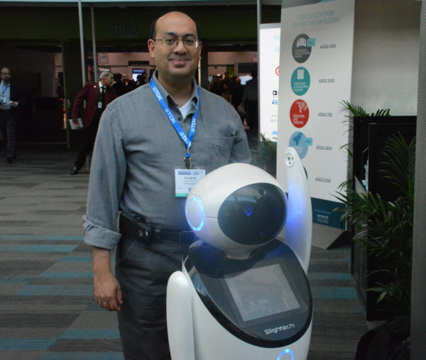 Eugene Demaitre, senior editor of Robotics Business Review, poses at Sensors 2018 with Sdeno robot