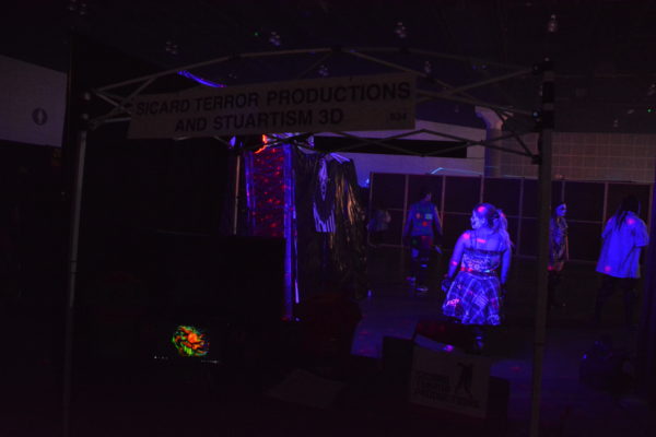 Zombie performers in lights near "Sicard Terror" booth at ScareLA™ 2018