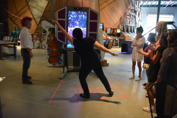 Woman spreads her arms and stands on one foot to play'Super Thunder Fox" at Micro Amusement Park™