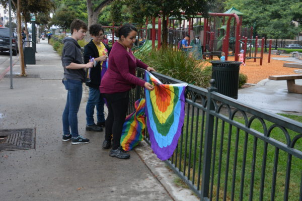 Volunteers hang rainbow bunting on the Central Park fence at San Gabriel Valley Pride 2018