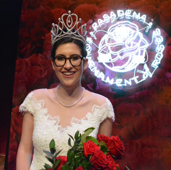 Newly-crowned Rose Queen Louise Deser Siskel holds her rose bouquet near Tournament of Roses logo
