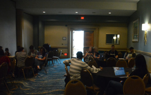 Teachers sit around three round tables in a conference room