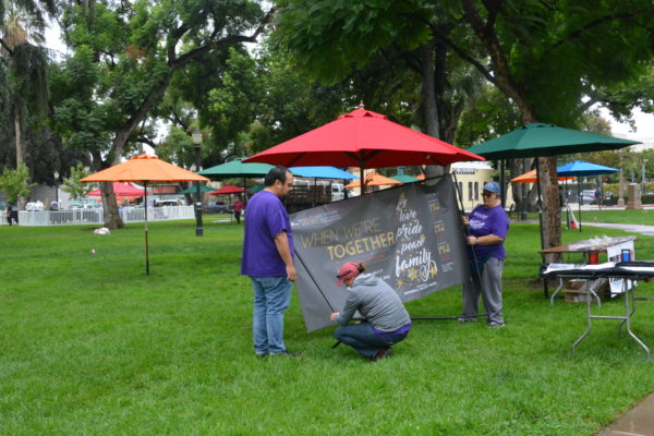 exhibitors set up a sign under a red umbrella at San Gabriel Valley Pride 2018