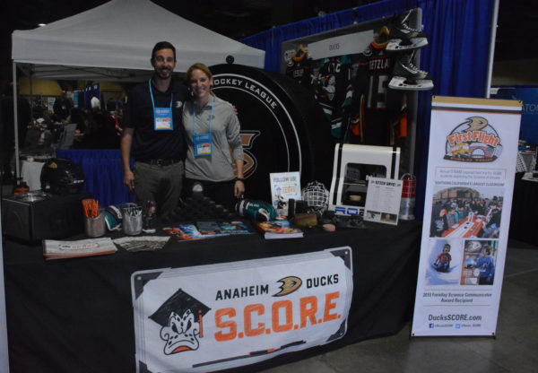 Exhibitors Jason Cooper and Molly Schaus smile from Anaheim Ducks S.C.O.R.E. exhibit at California STEAM Symposium 2018