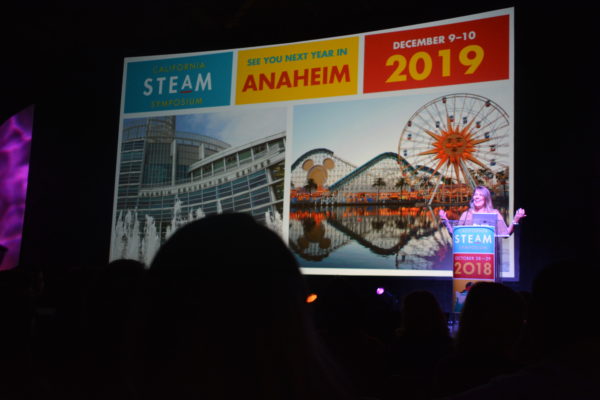 Shelly Masur laughs as slide revealing "California STEAM Symposium, Anaheim 2019" is revealed