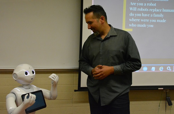 Pepper robot raises her hands as roboticist Walter Martinez "talks" to her