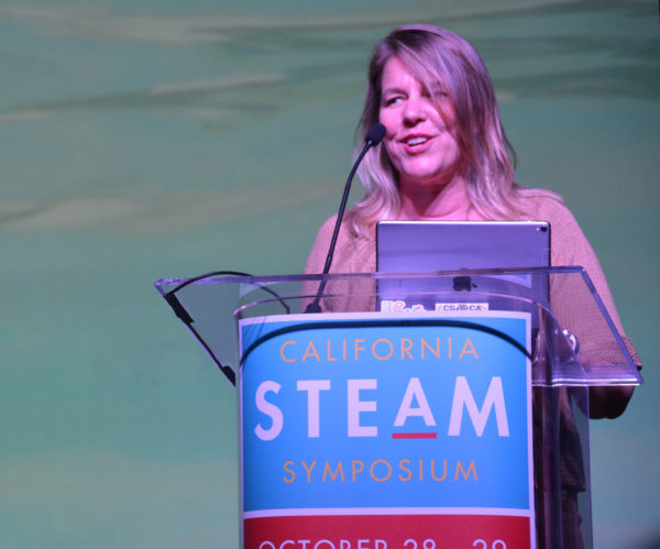 Shelly Masur smiles from California STEAM Symposium podium