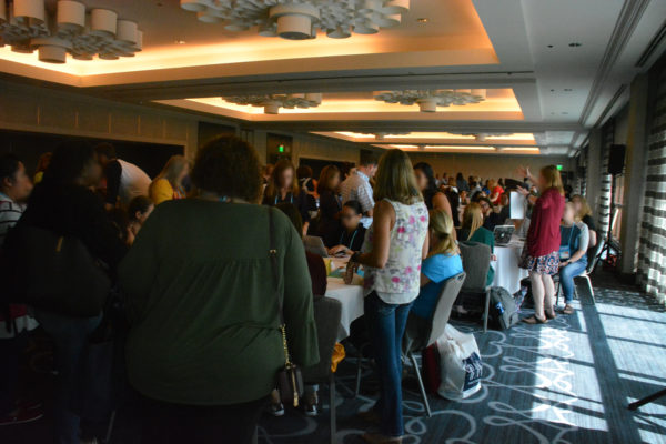 Teachers crowd around round tables of resources at California STEAM Symposium