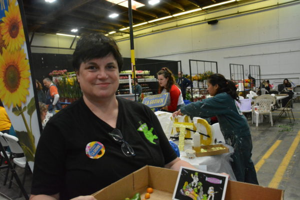 Cal poly mom Monica Kauppinen shows visitors a cardboard box full of sample plant materials as daughter Melittaworks with fellow students in the background