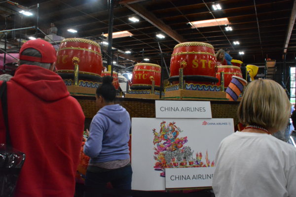 Red drums on the China Airlines float as visitors look on at the rendering of the float concept on an easel