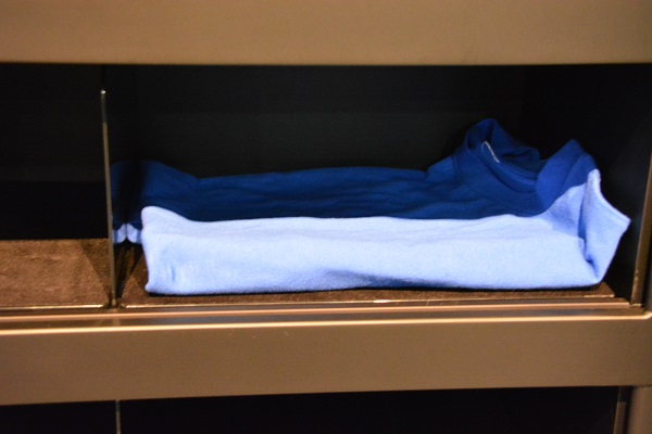 Closeup of folded blue polo shirt inside the "Laundroid"'s drawer after the robot completes a folidng cycle