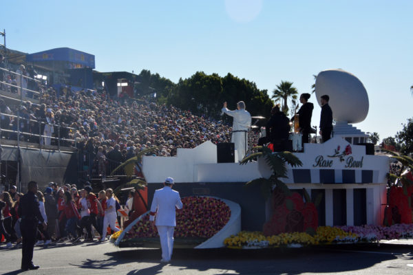 Anne Marie waves to audience from atop float with representation of Rose Bowl stadium on it at end of her performance