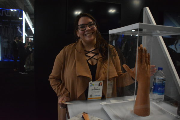 Ella Scarchilli of Arrow Electronics smiles from exhibit of customizable prosthetic arm at Eureka Park show exhibit