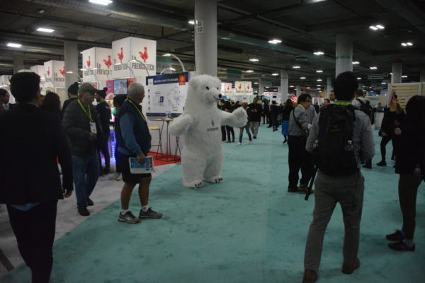 Show attendees stroll through Eureka Park startup area as white costumed polar bear mascot greets them