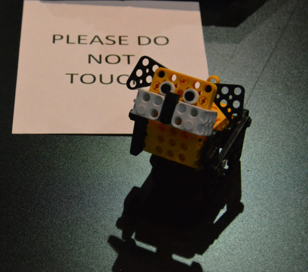 Robotis yellow mini dog robot displayed near a "Please do not touch" sign