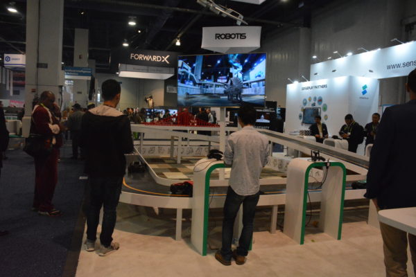 Robotis exhibit with men looking at robotic vehicle track