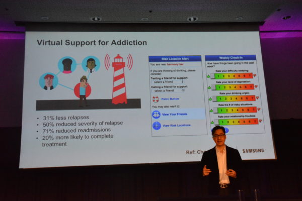 Dr. David Rhewy before slide that details the app pinponting a user's location and offering warnings such as, "You are near Harmony Bar. and a pull-down menu to select a friend to text "if you are thinking of drinking", during his presentation at Virtual Medicine 2019.." at Virtual Medicine 2019