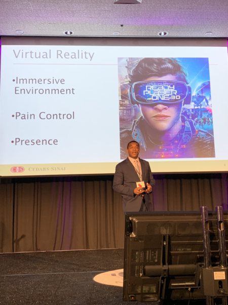 Dr. Little with slide reading, "Immersive Environment"; "Pain Control"; "Presence" and "Ready Player One" image during his presentation at Virtual Medicine 2019
