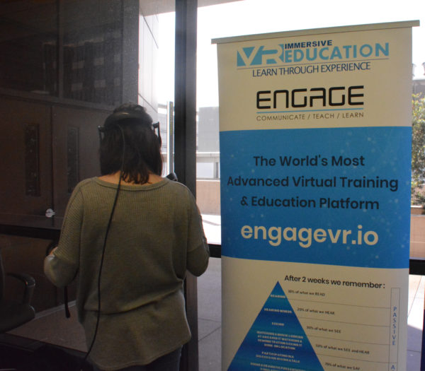 Woman wears headset near ENGAGE VR sign