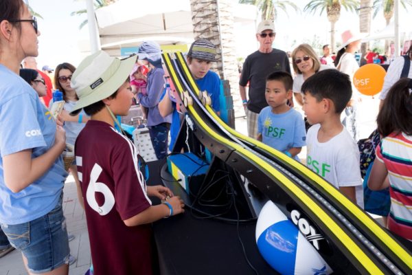 Three boys stand near a "racetrack" for robotic vehicles at OC STEAM Fest