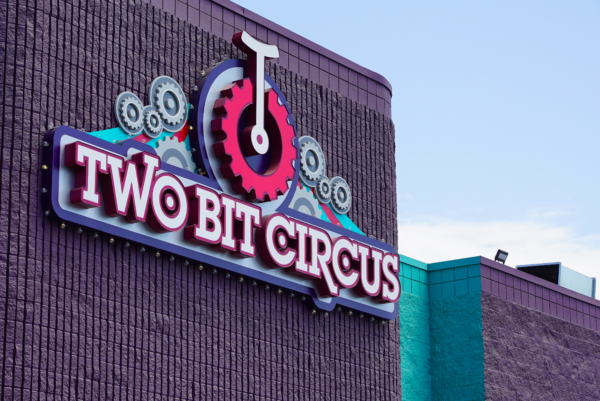 Closeup of Two Bit Circus sing on their Micro Amusement Park building with red unicycle emblem