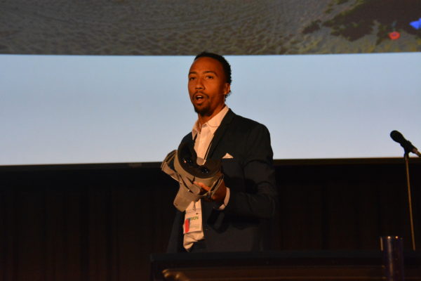 Closeup of Harmon Clarke in a business suit with a VR headset in his hands.