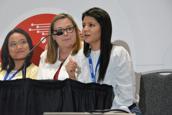 Melissa speking into mic as Jocelyn and Melanie listen